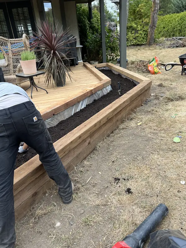 Angled raised timber bed wrapping around a deck corner