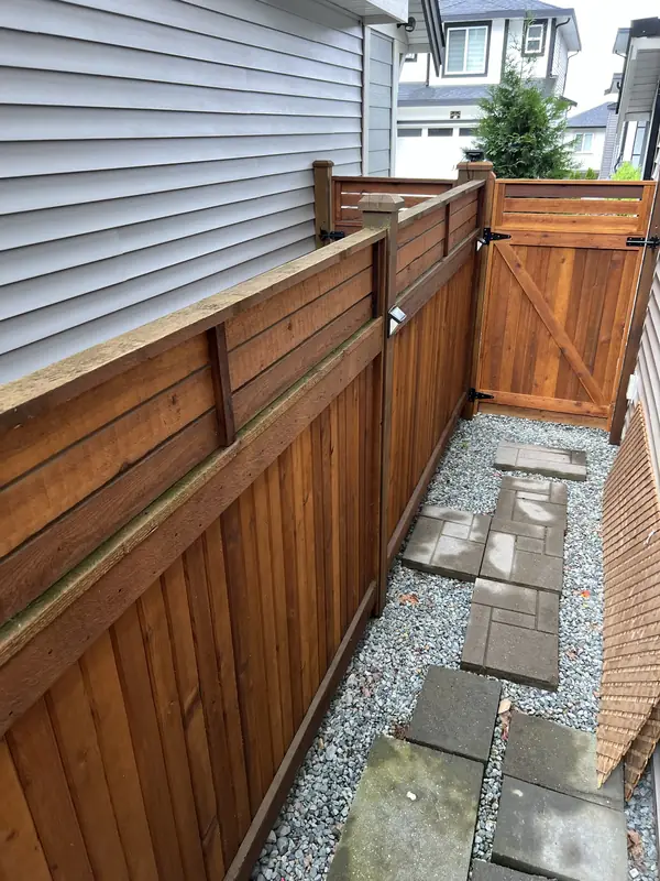 Stained cedar privacy fence with a horizontal slat top and matching gate along a side yard