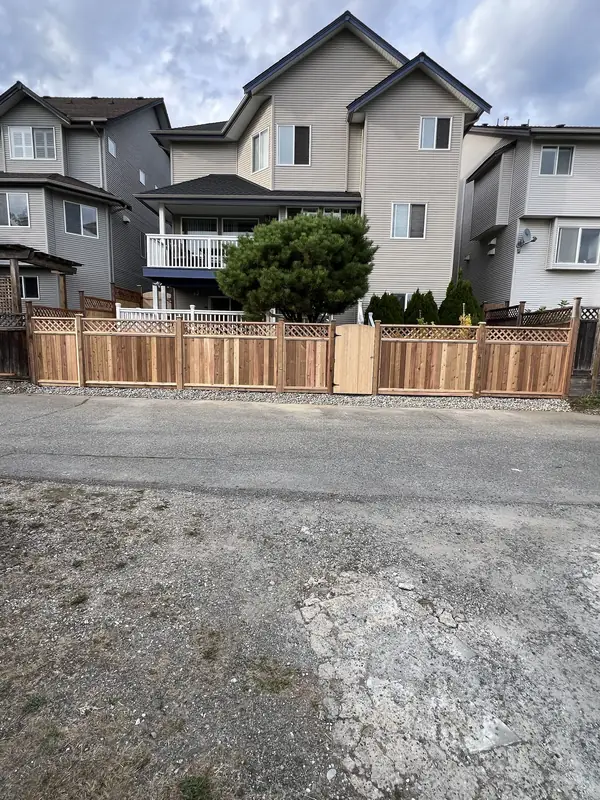 New lattice-top cedar fence across the back of a house, seen from the lane