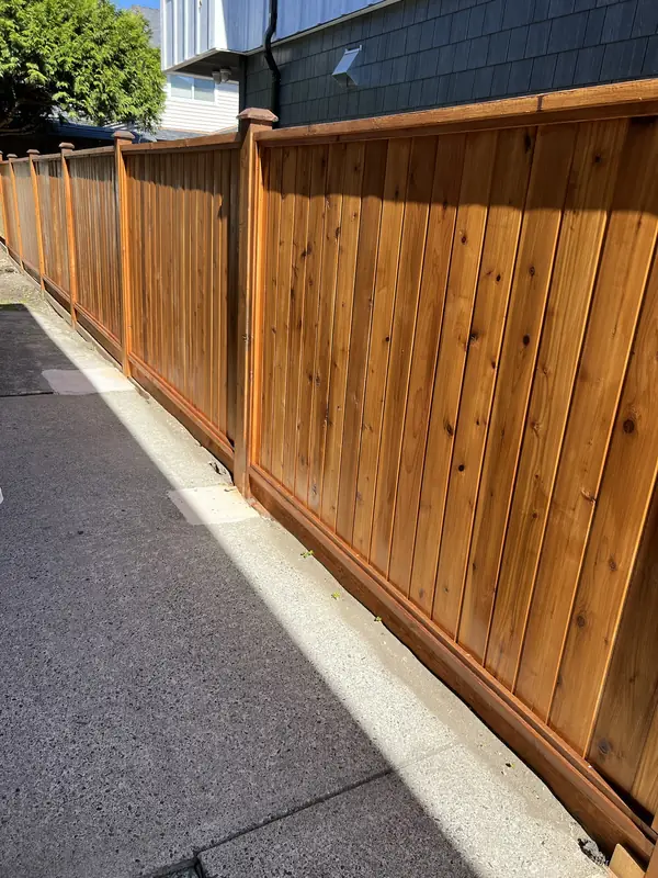 Stained cedar privacy fence with a cap rail beside a house