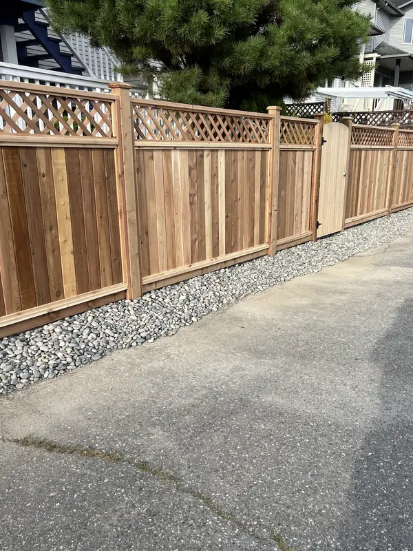 Lattice-top cedar fence along a lane with a gravel strip along its base