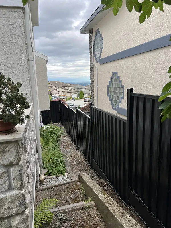 Black steel privacy fence stepping down a sloped side yard