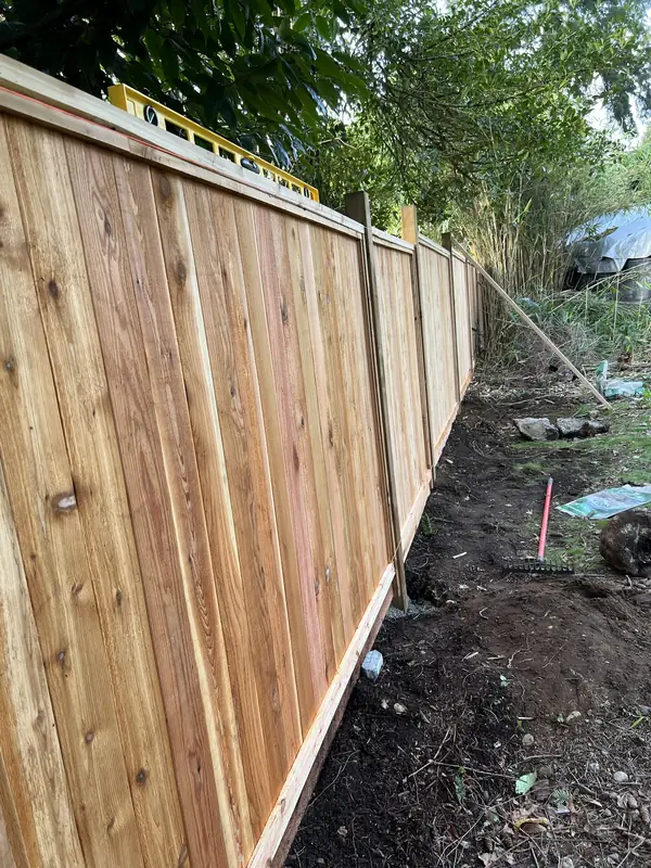 New cedar fence panels going up between posts, with a level on top