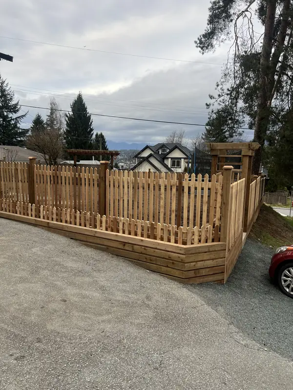 Full run of cedar picket fence on a timber wall around a corner lot, with an arbour at the far end