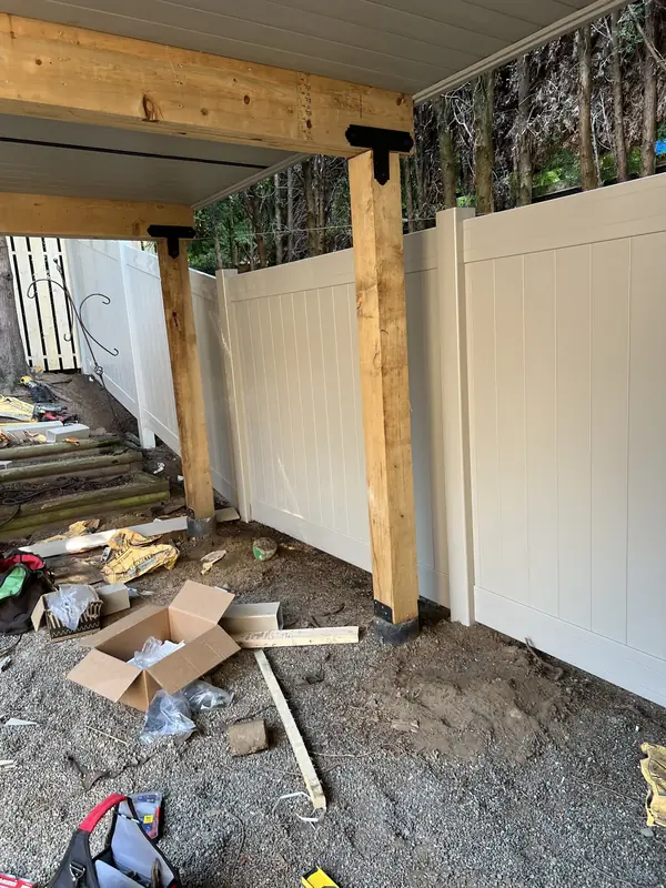 White vinyl privacy fence going in under a deck, beside new support posts