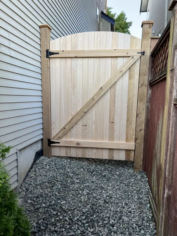 Inside of an arched cedar gate showing its Z-brace frame and black hinges