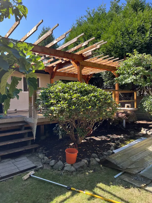 Wood pergola with its old roof panels removed and stacked on the lawn