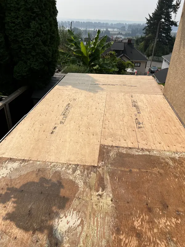 New plywood sheathing going down over weathered old plywood on a flat roof